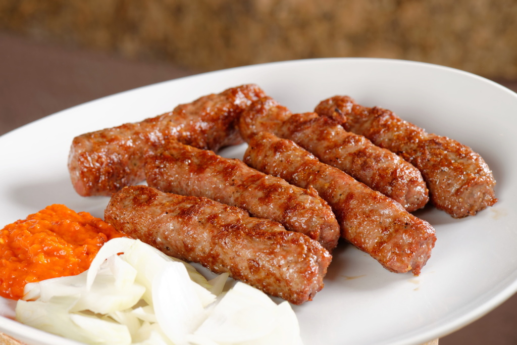 Traditional cevapcici with ajvar paste and onion